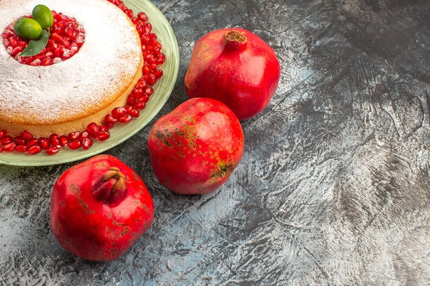 Seitliche Nahaufnahme rote Granatäpfel drei rote Granatäpfel neben dem appetitlichen Kuchen