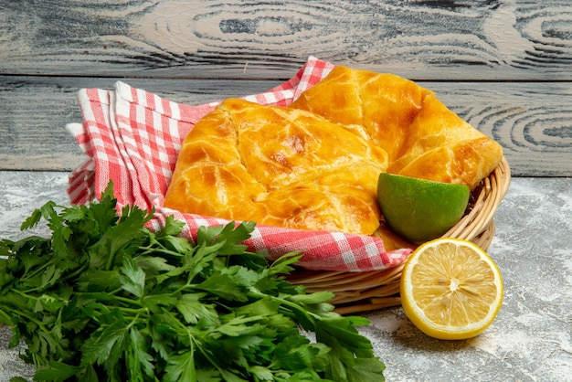 Seitliche Nahaufnahme Torten und Zitronen Holzkorb mit appetitlichen Torten Kräuter Zitrone und Limette und Tischdecke auf dem Holzhintergrund