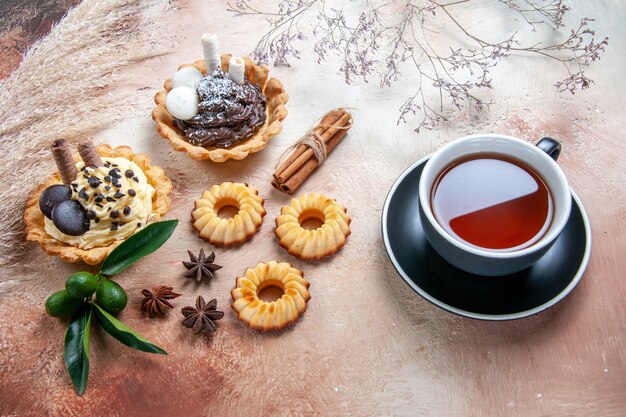 Seitliche Nahaufnahme versüßt eine Tasse Tee Cupcakes Kekse Zitrusfrüchte Sternanis
