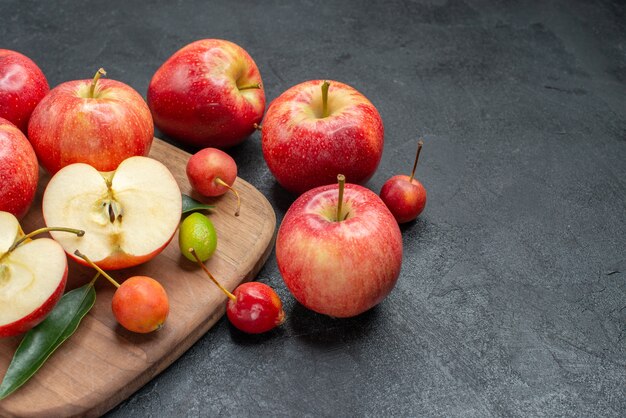 Seitliche Nahaufnahmefrüchte Früchte Früchte Beeren auf dem Brett neben den Äpfeln mit Blättern