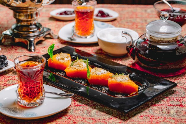 Seitlicher Dessert süß gebackener Kürbis mit Nüssen und Sahne und zwei Gläsern Tee