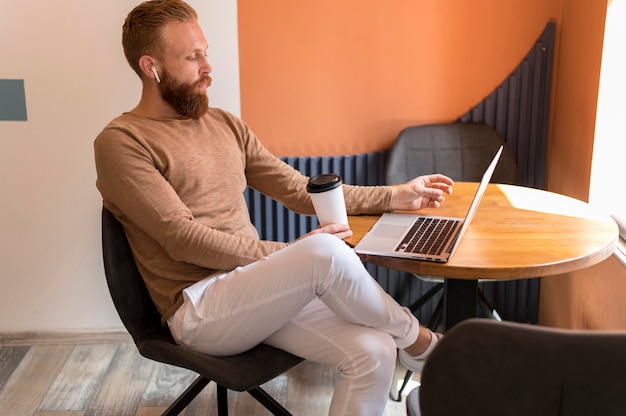 Seitwärts bärtiger Mann, der am Laptop arbeitet