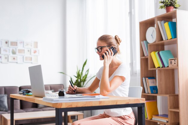 Seitwärts blonde Frau, die am Telefon spricht