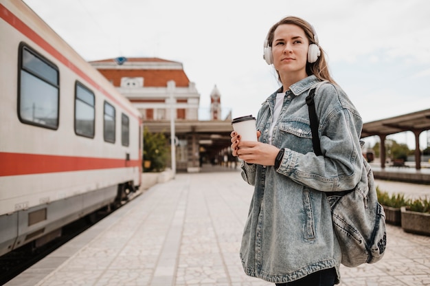 Kostenloses Foto seitwärts frau, die musik am bahnsteig hört