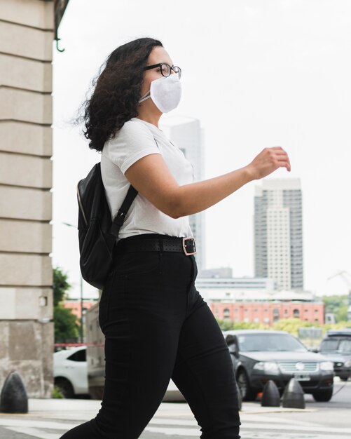 Seitwärts junge Frau, die eine medizinische Maske im Freien trägt