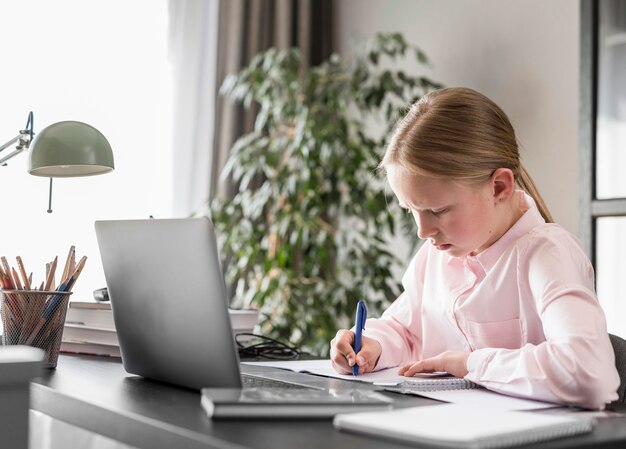 Seitwärts kleines Mädchen, das an Online-Klasse teilnimmt