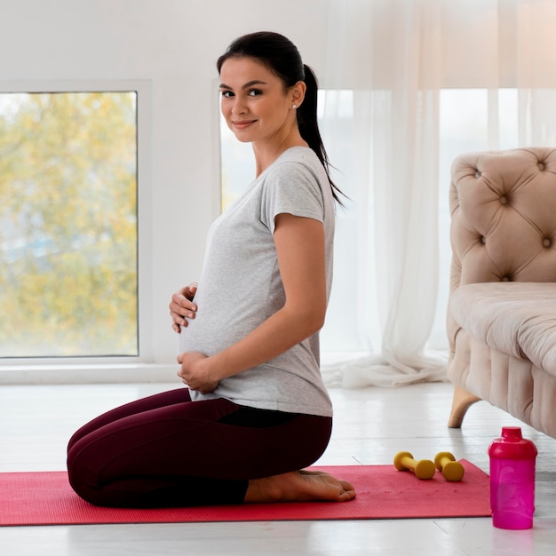 Seitwärts schwangere Frau, die Yoga macht