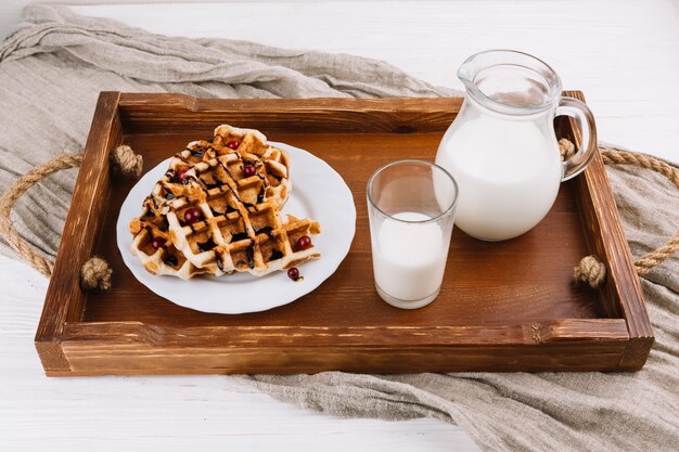 Selbst gemachte belgische Waffeln mit frischer Milch auf hölzernem Behälter