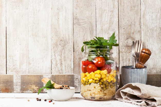 Selbst gemachte gesunde Schicht Salat in Einmachglas auf einem hölzernen Hintergrund