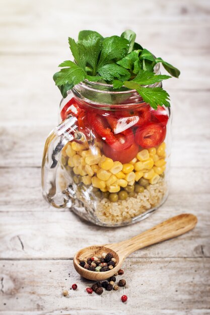 Selbst gemachte gesunde Schicht Salat in Einweckgläser auf einem hölzernen backgroun