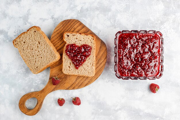 Selbst gemachte Himbeermarmelade mit frischen Himbeeren auf konkreter, Draufsicht