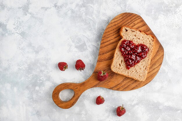 Selbst gemachte Himbeermarmelade mit frischen Himbeeren auf konkreter, Draufsicht