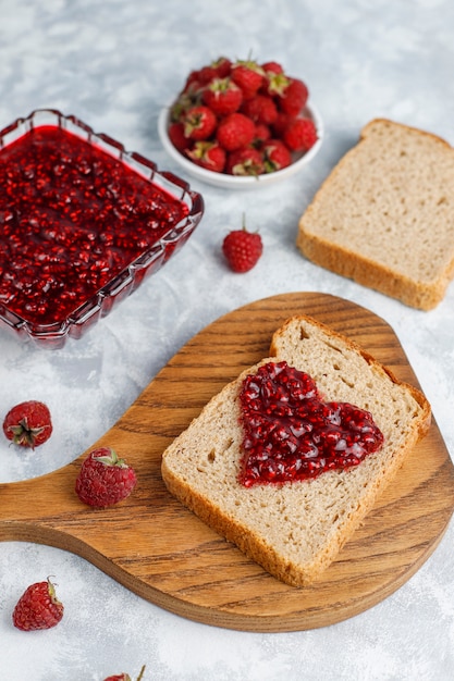 Selbst gemachte Himbeermarmelade mit frischen Himbeeren auf konkreter, Draufsicht