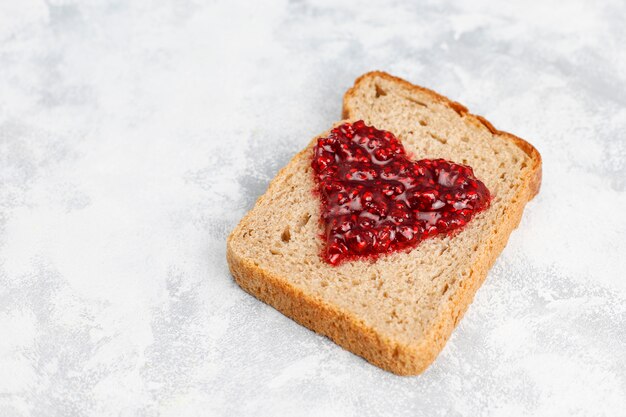 Selbst gemachte Himbeermarmelade mit frischen Himbeeren auf konkreter, Draufsicht