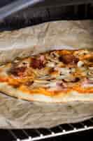 Kostenloses Foto selbst gemachte pizza auf pergamentpapier über dem gitter