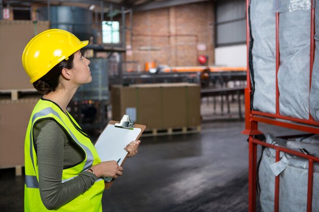 Selbstbewusste Arbeiterin, die Produkte im Lager untersucht