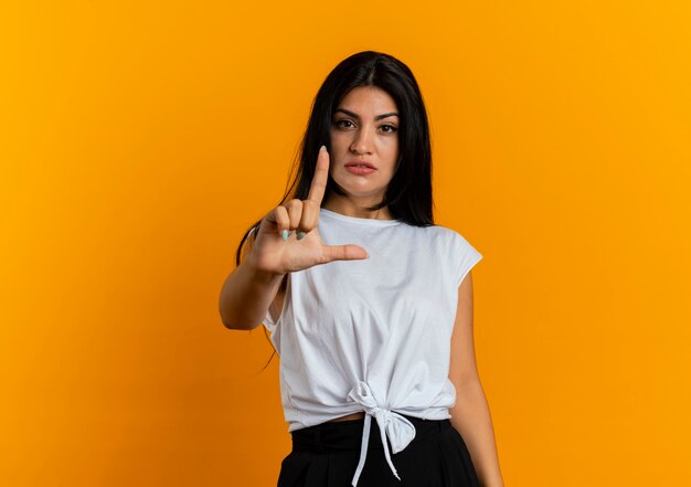 Selbstbewusste junge kaukasische Frau gestikuliert Waffenhandzeichen nach oben