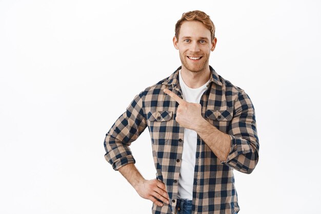 Selbstbewusster, attraktiver Mann mit roten Haaren und Bart, der mit dem Finger auf die obere linke Ecke zeigt und ein neues Promo-Deal-Shop-Angebot zeigt, das Werbetext auf weißem Hintergrund zeigt