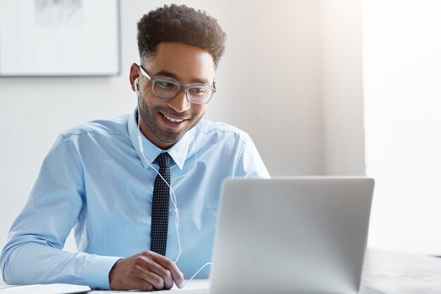 Selbstbewusster Geschäftsmann, der an seinem Laptop arbeitet