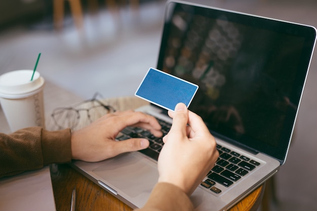 Selbstbewusster geschäftsmann, der online mit kreditkarte mit laptop im café einkauft