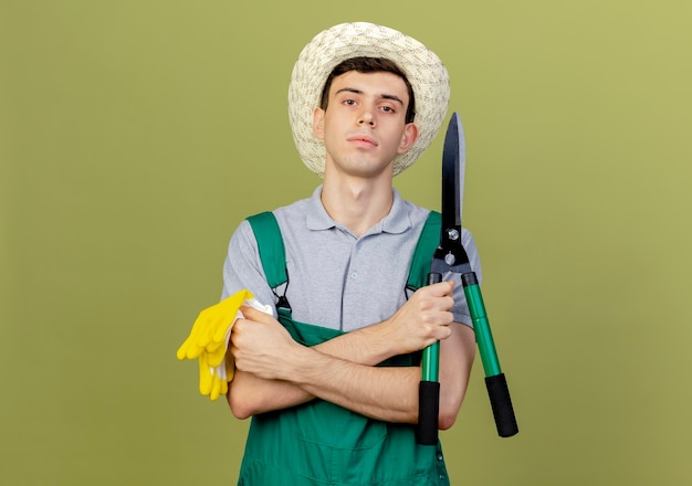 Selbstbewusster junger männlicher Gärtner mit Gartenhut steht mit verschränkten Armen