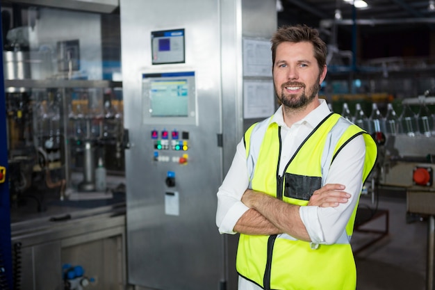 Selbstbewusster männlicher Arbeiter, der in der Fabrik steht