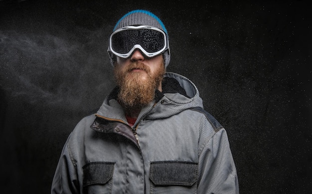 Kostenloses Foto selbstbewusster snowboarder mit voller schutzausrüstung, isoliert auf dunklem, strukturiertem hintergrund.