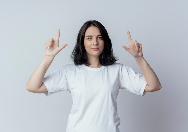 Selbstbewusstes junges hübsches kaukasisches Mädchen, das mit den Fingern oben lokalisiert auf weißem Hintergrund zeigt