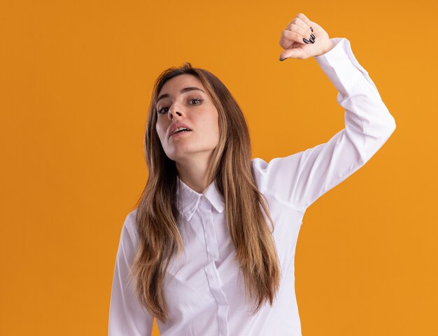 Selbstbewusstes junges hübsches kaukasisches Mädchen steht mit erhobener Hand, die auf sich auf Orange zeigt