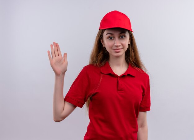 Selbstbewusstes junges Liefermädchen in der roten Uniform, die Hi-Geste auf isoliertem Leerraum tut