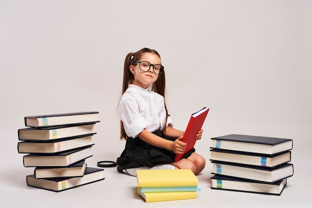 Selbstbewusstes Mädchen, das zwischen Büchern sitzt