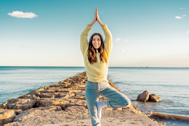 Selektive Fokusaufnahme einer attraktiven Frau in einer Yoga-Pose an einem Strand in Benicassim, Spanien