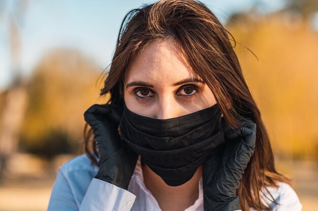 Selektive Fokusaufnahme einer jungen Dame in einem Park, die eine Hygienemaske trägt - Konzept der neuen Normalität