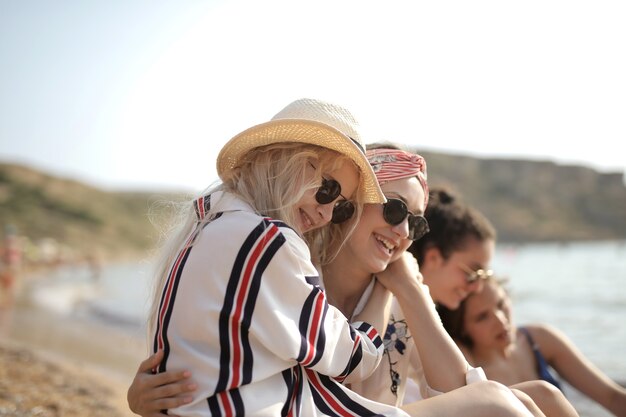 Selektive Fokusaufnahme von zwei jungen Frauen, die sich am Strand sitzend umarmten