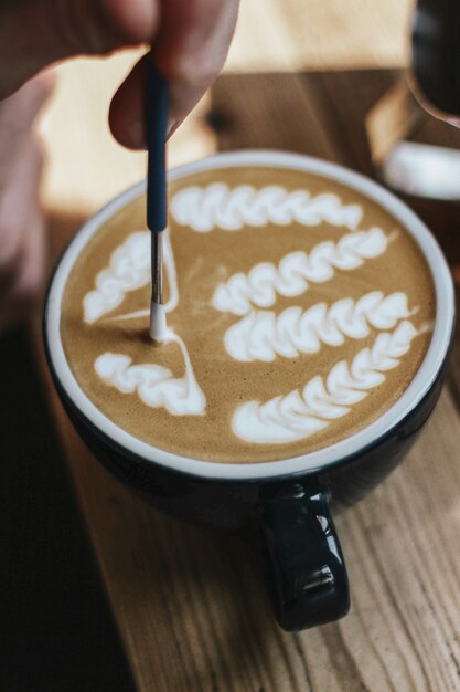 Selektive Nahaufnahme des Kaffees mit Latte Art in einer schwarzen Keramikschale auf einer Holzoberfläche