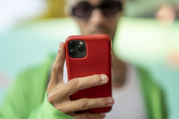 Selektiver Fokus einer Person, die das Smartphone in einem roten Gehäuse betrachtet
