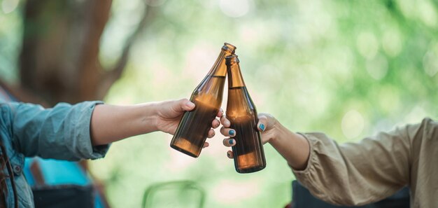 Selektiver Fokus und Nahaufnahme Hände von Frauen und Freunden, die sich vor dem Campingzelt entspannen Sie genießen es, mit Spaß und Freude zusammen zu jubeln und Bier zu trinken