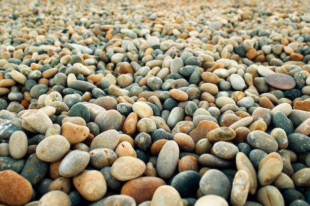 Selektiver Fokusschuss der Nahaufnahme von runden kleinen Kieselsteinen am Strand