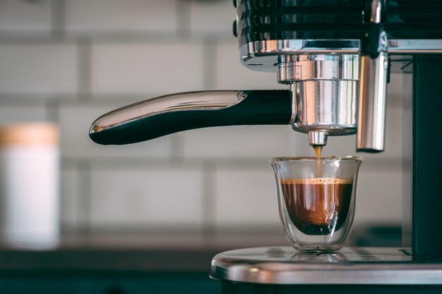 Selektiver Fokusschuss einer Espressomaschine, die am Morgen leckeren warmen Kaffee macht