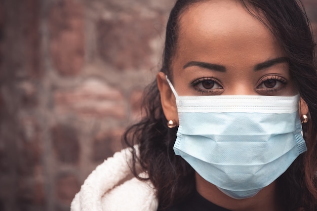 Selektiver Fokusschuss einer jungen Frau, die eine medizinische Maske trägt - bleiben Sie sicheres Konzept