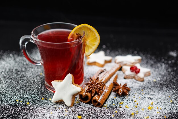 Selektiver Fokusschuss einer Tasse Tee mit köstlichen Keksen, Anissternen und Zimtstangen