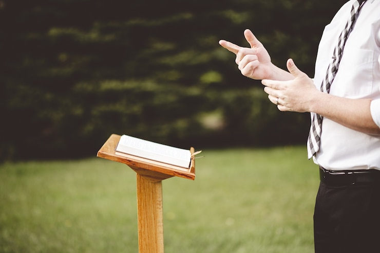 Kostenlose Foto selektiver fokusschuss eines jungen mannes, der vor einem hölzernen kirchenstand steht