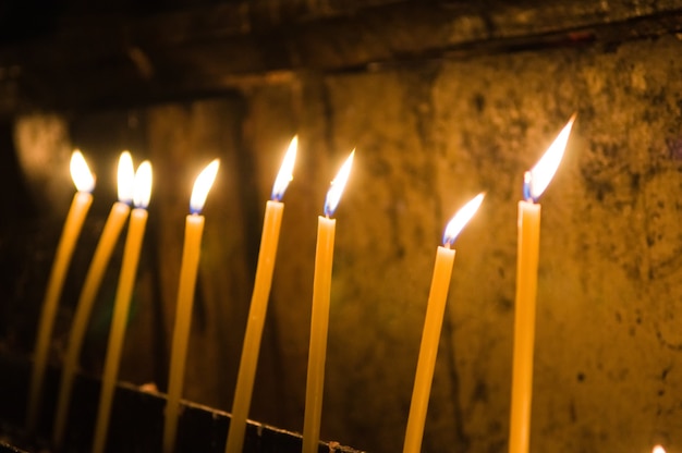 Selektiver Fokusschuss von brennenden gelben Kerzen innerhalb der Kirche