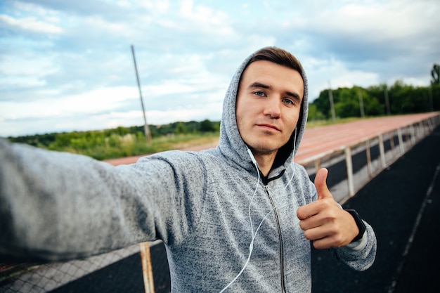 Kostenloses Foto selfie eines hübschen sportlers, der einen daumen, beim hören musik zeigt