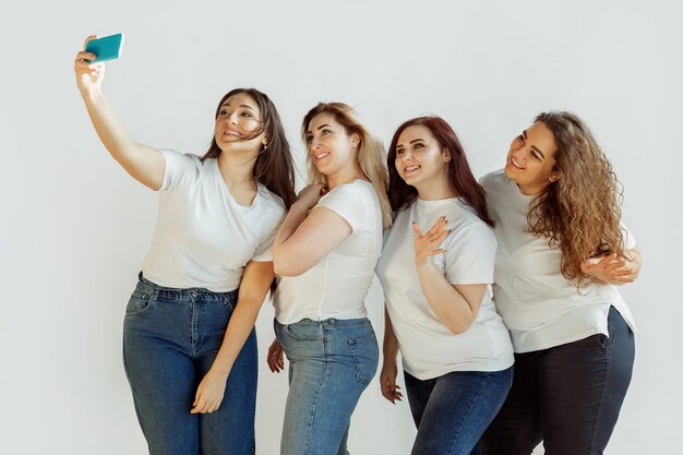 Selfie. Junge kaukasische Frauen in der Freizeitkleidung, die Spaß zusammen haben. Freunde, die auf weißem Hintergrund posieren und lachen, sehen glücklich und gepflegt aus. Bodypositiv, Feminismus, sich selbst lieben, Schönheitskonzept.