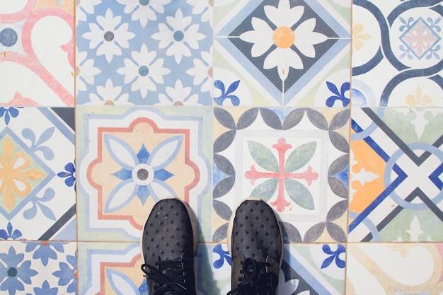 Selfie von füßen mit sneaker schuhe auf vintage kunst muster fliesen boden, draufsicht