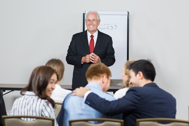Senior Business-Mann mit einer weißen Tafel lächelnd hinter