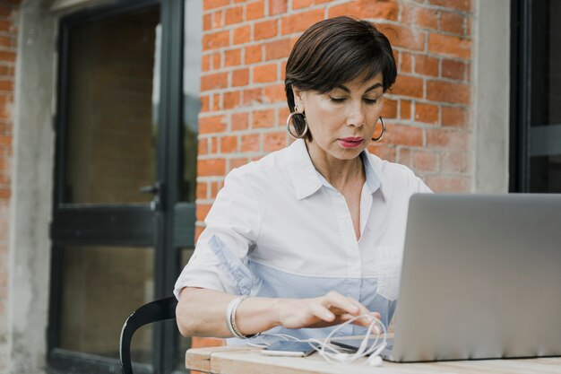 Senior, der draußen mit Laptop sitzt