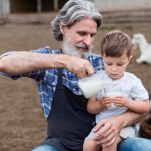 Senior gießt Milch für niedlichen Jungen