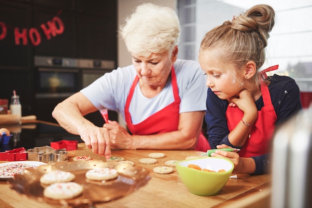 Senior und Mädchen bereiten Weihnachtsplätzchen vor